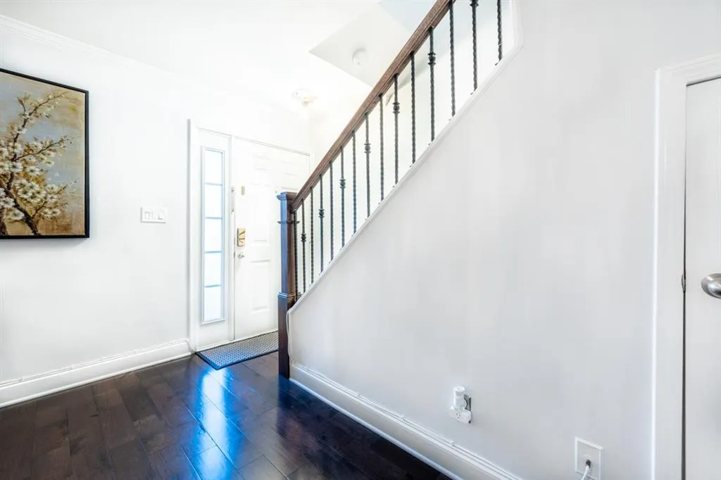 Foyer featuring dark wood-type flooring, stairway, and baseboards