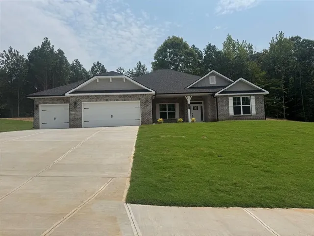 Brick exterior with gabled rooflines, two-car garage, concrete driveway, and front lawn