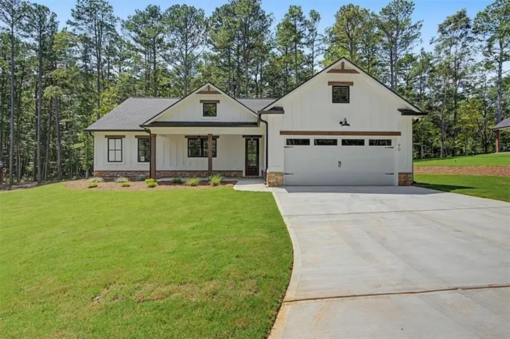 Contemporary farmhouse exterior with white board and batten siding, dark framed windows, a two-car garage, stone accents, and a concrete driveway