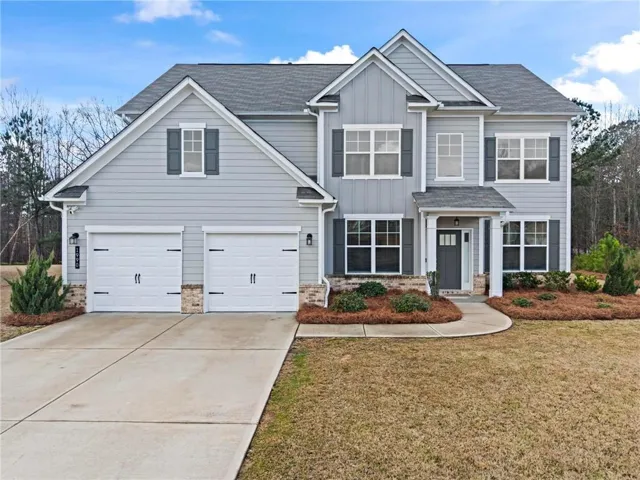 Two-story residence featuring light gray siding, dark shutters, and a covered entry with white columns