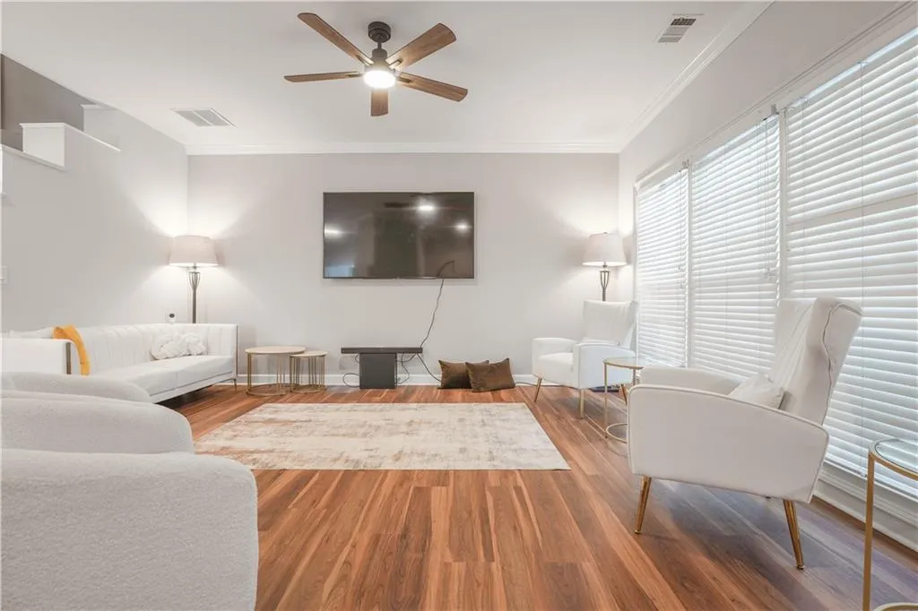 Living room with ornamental molding, ceiling fan, and wood finished floors
