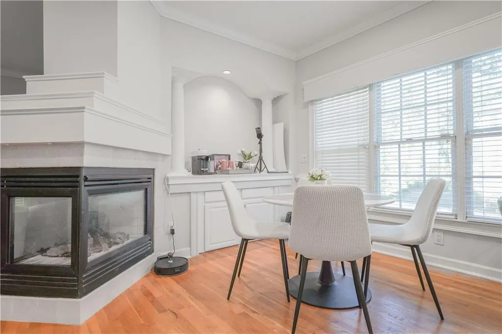 Dining area with crown molding, a multi sided fireplace, light wood-type flooring, and recessed lighting