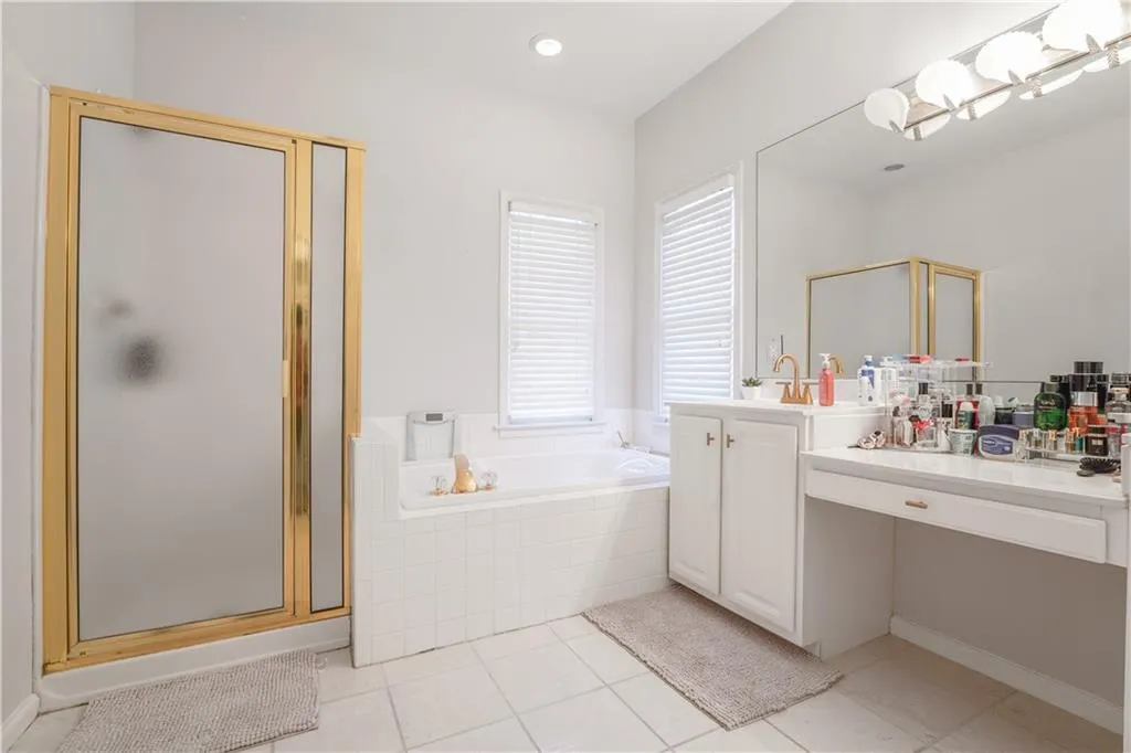 Bathroom with vanity, a shower stall, a garden tub, light tile patterned flooring, and recessed lighting