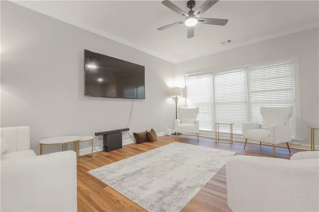 Living area with crown molding, light wood finished floors, and ceiling fan