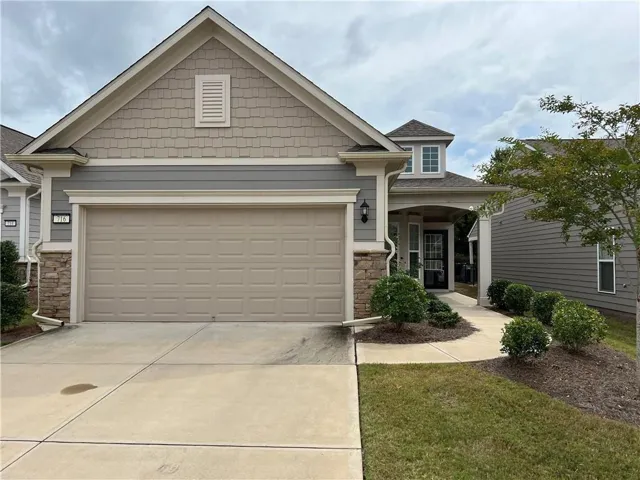 Architectural facade with shake siding and stone accents, featuring an integrated garage and a covered entry