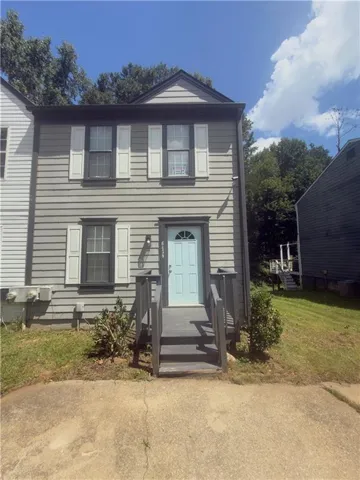 Two-story exterior with horizontal siding, light blue entry door, and white louvered shutters