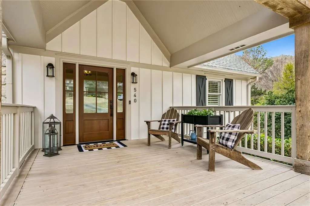 Doorway to property with a deck, board and batten siding, and roof with shingles