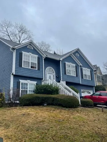 Two-story residence featuring blue siding, white trim, and black window shutters