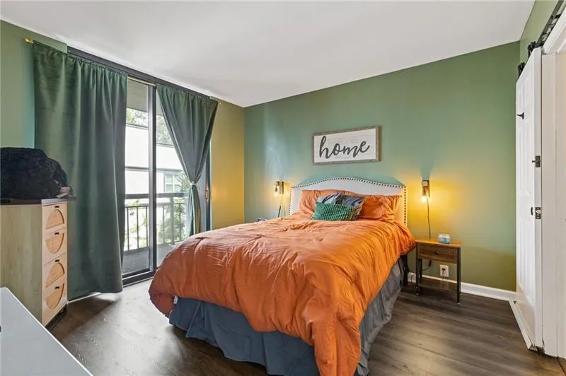 Bedroom featuring dark wood-style floors, access to exterior, and a barn door