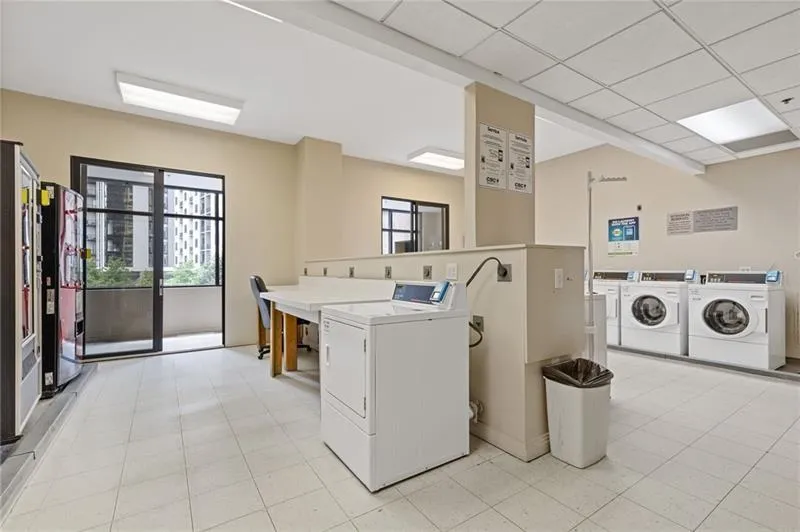 Communal laundry room featuring independent washer and dryer and a drop ceiling