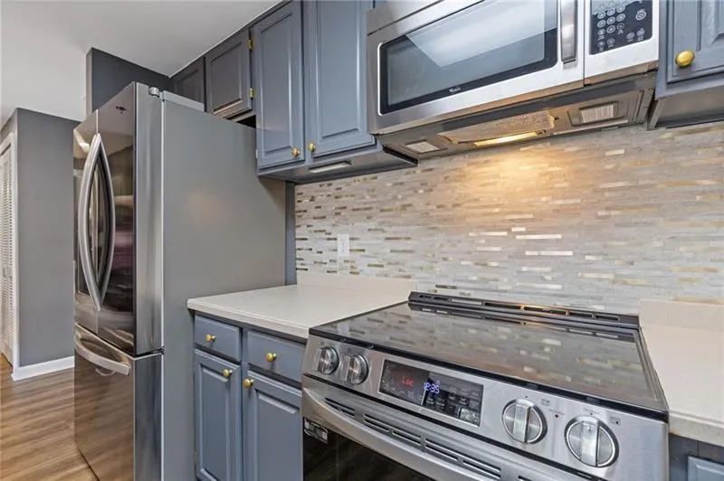 Kitchen with stainless steel appliances, light countertops, tasteful backsplash, and light wood-type flooring