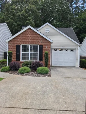 Brick and siding exterior featuring a white garage door with decorative glass inserts