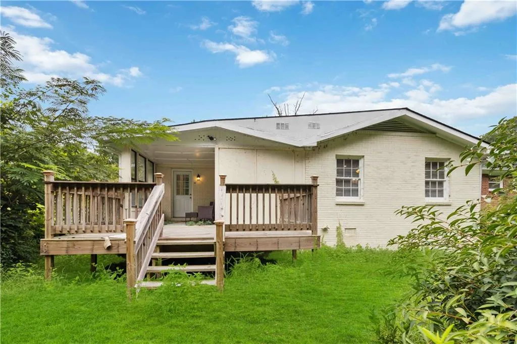 Rear view of property with brick siding, a deck, a lawn, and crawl space