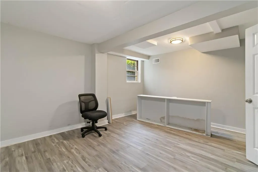 Unfurnished room featuring light wood-style floors and beamed ceiling