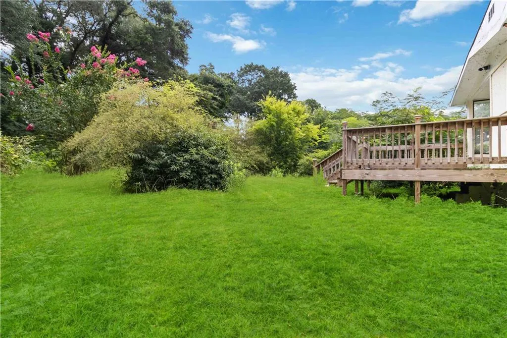 View of green lawn featuring a wooden deck