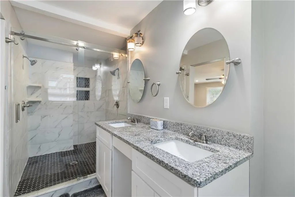 Bathroom featuring a marble finish shower and double vanity