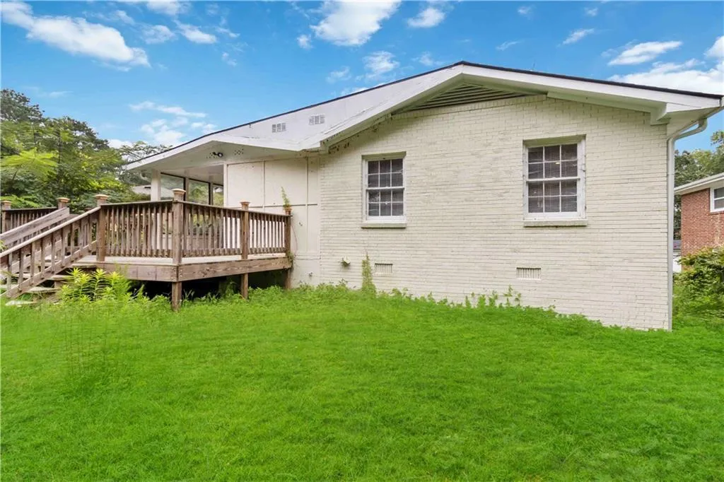 Rear view of property featuring a wooden deck, a yard, crawl space, and brick siding