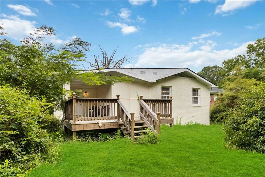 Rear view of house with a lawn, brick siding, a wooden deck, and crawl space