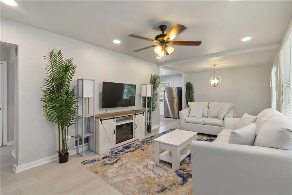 Living area with recessed lighting, a ceiling fan, light wood-style floors, and a glass covered fireplace