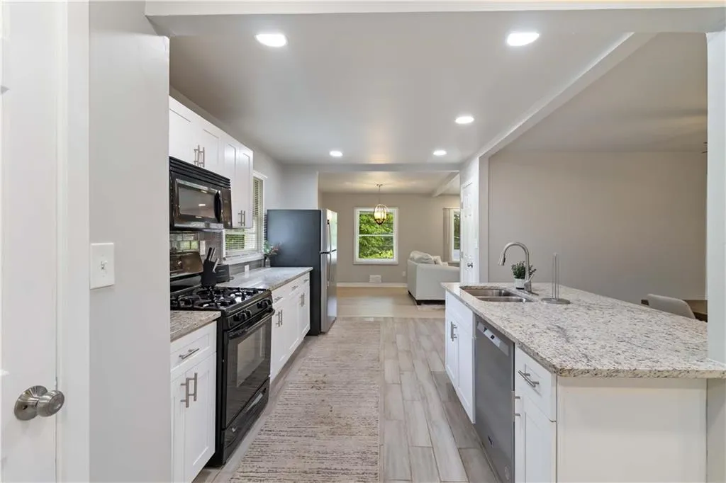 Kitchen featuring white cabinetry, black appliances, recessed lighting, light stone countertops, and light wood-style floors