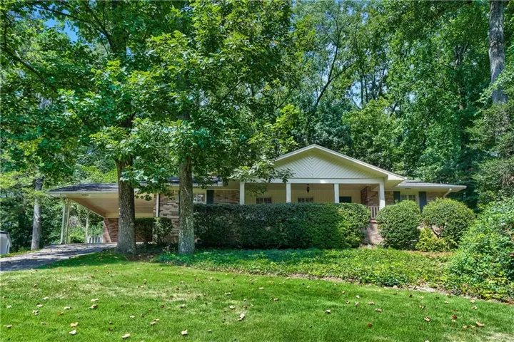 Ranch-style residence featuring a covered front porch, brick and siding exterior, carport, and mature landscaping