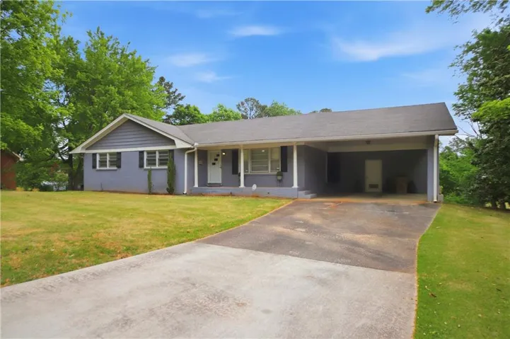 Ranch-style residence featuring a gray exterior, white trim, and a prominent carport