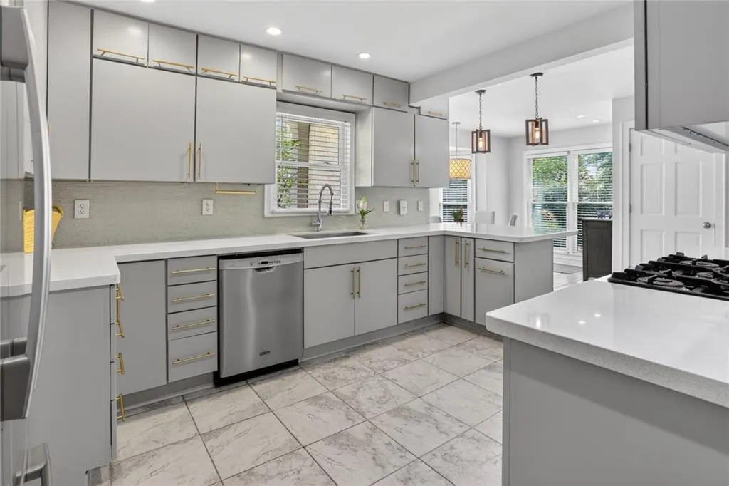 Kitchen featuring gray cabinetry, stainless steel appliances, pendant lighting, tasteful backsplash, and a peninsula