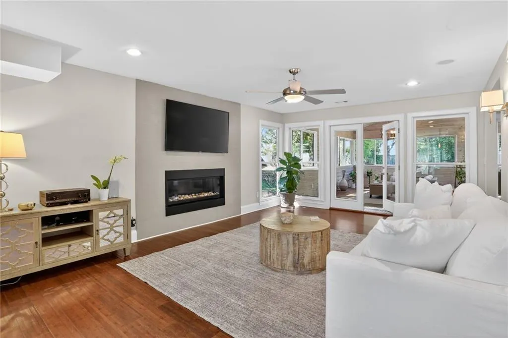 Living room with dark wood-style floors, a ceiling fan, a fireplace, and recessed lighting