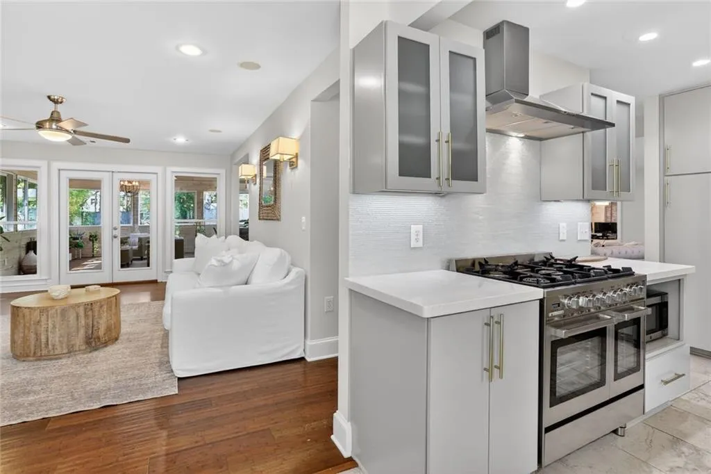 Kitchen featuring stainless steel appliances, glass fronted cabinets, gray cabinetry, ceiling fan, and open floor plan