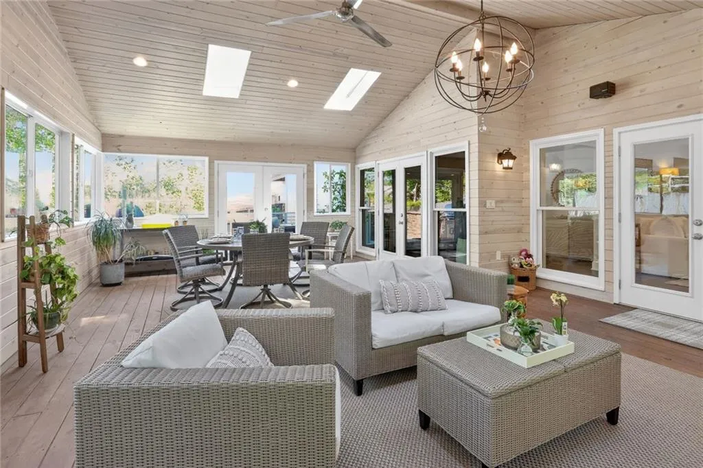 Sunroom / solarium with french doors, a vaulted wood ceiling, a skylight, hardwood / wood-style flooring, and wood walls