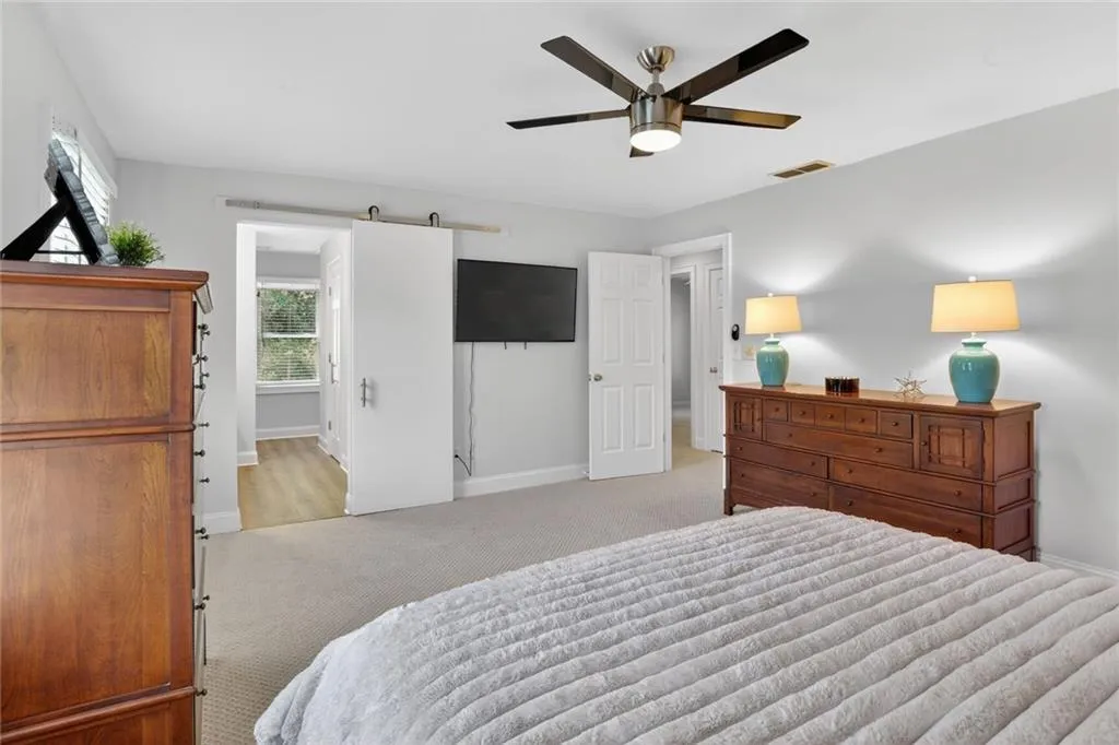 Bedroom with a barn door, a ceiling fan, and carpet