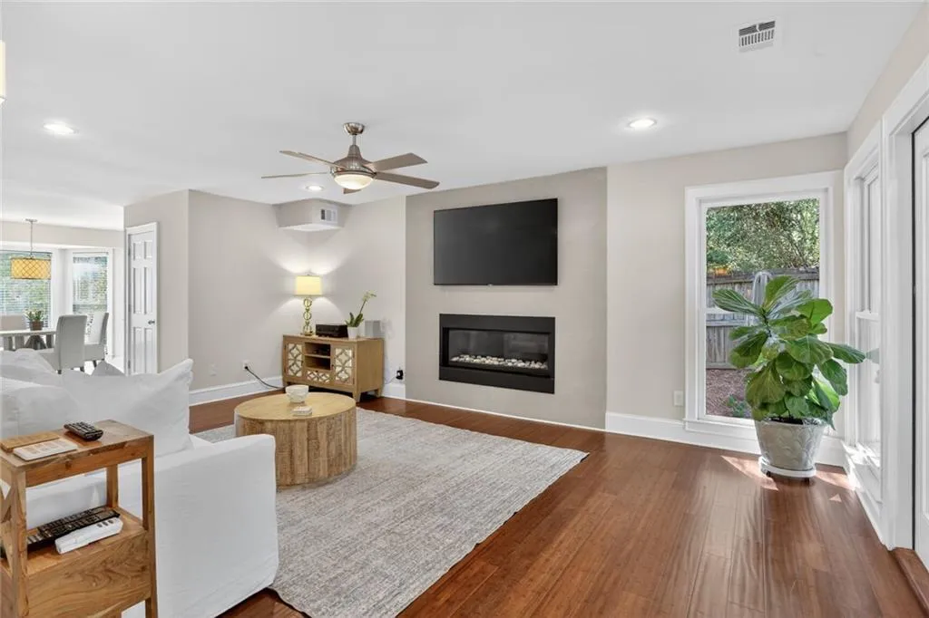 Living area with ceiling fan, a large fireplace, hardwood / wood-style flooring, and recessed lighting
