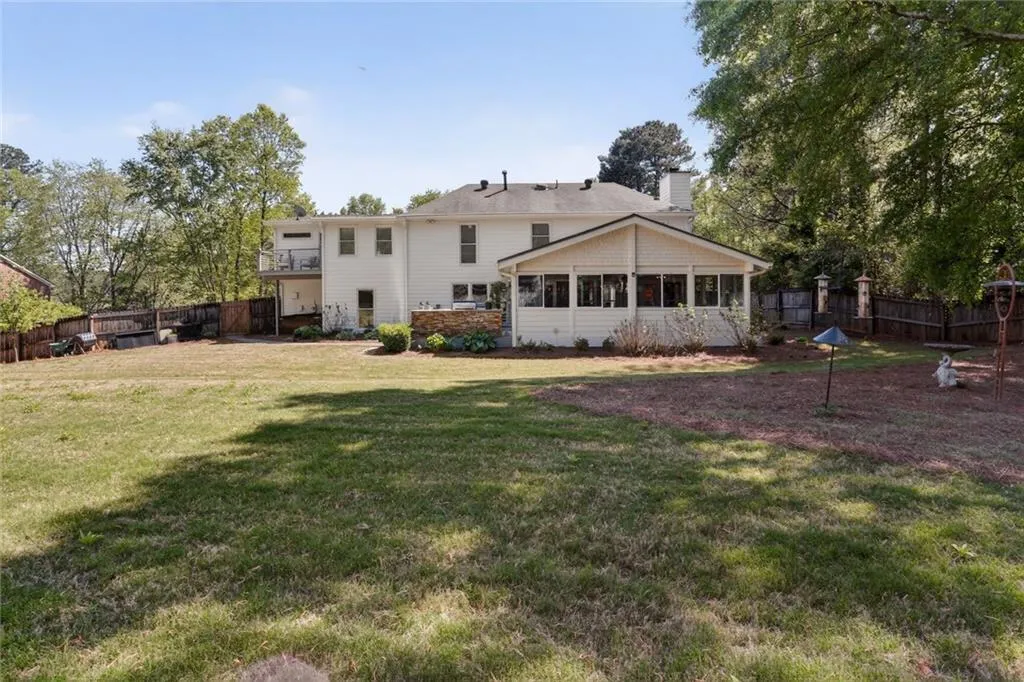 Rear view of property featuring a fenced backyard, a sunroom, and a chimney