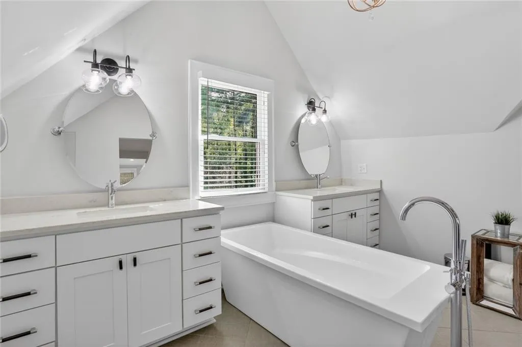 Bathroom with two vanities, a soaking tub, and light tile patterned flooring