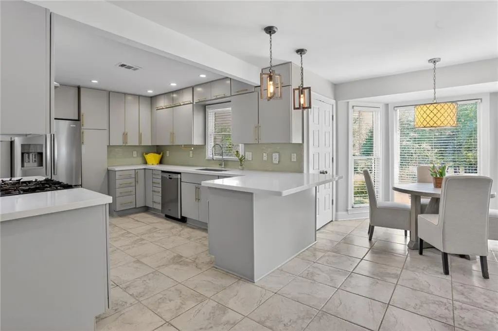 Kitchen featuring gray cabinetry, stainless steel appliances, a peninsula, and backsplash