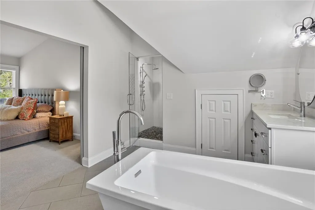 Bathroom featuring lofted ceiling, ensuite bath, vanity, light tile patterned floors, and tiled shower