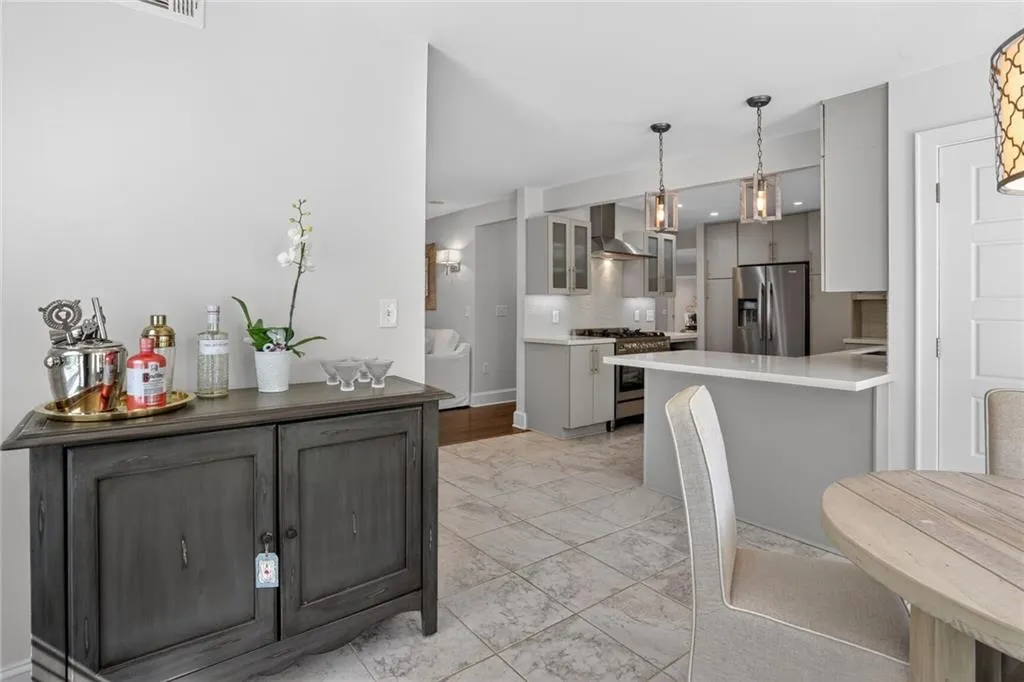 Kitchen with gray cabinetry, glass fronted cabinets, stainless steel appliances, and a peninsula