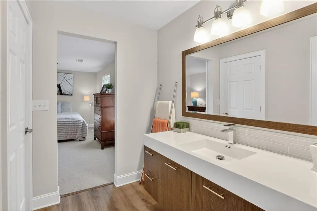 Ensuite bathroom with vanity, light wood finished floors, tasteful backsplash, and light colored carpet
