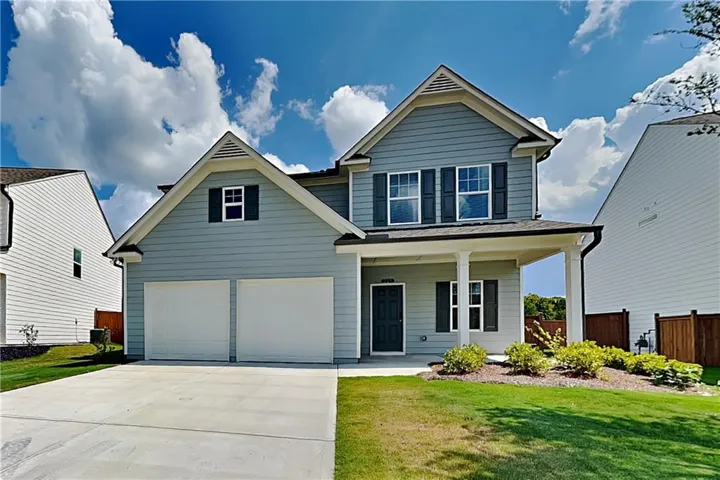 Two-story residence featuring light blue siding, a covered front porch, a two-car garage, and a concrete driveway