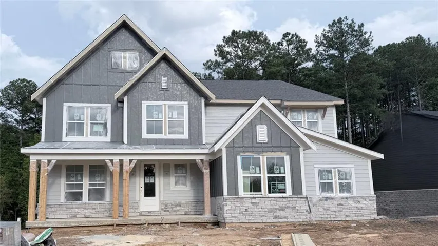 Two-story residential structure under construction featuring multiple gables and a covered front porch frame