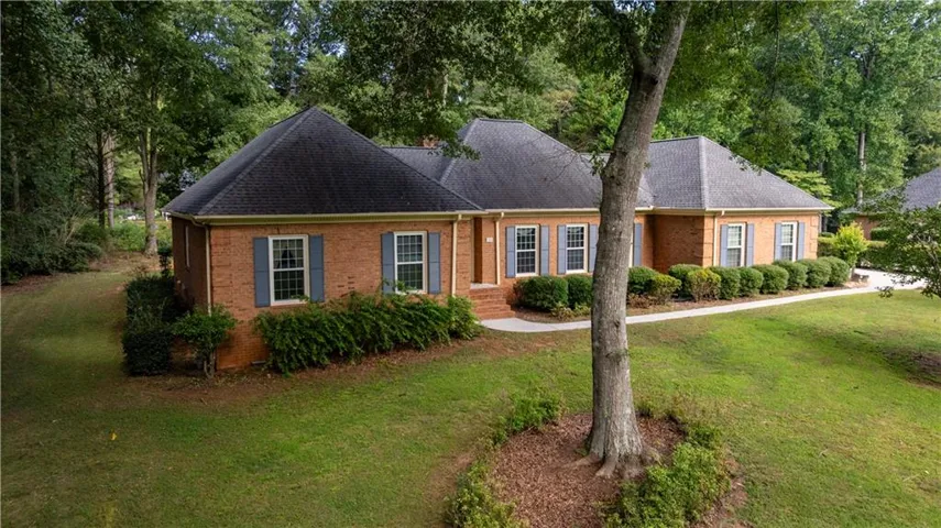 Brick exterior with a dark shingle roof, complemented by blue louvered shutters and white window trim