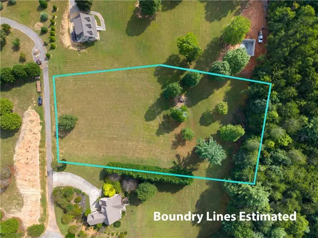 Expansive land parcel featuring a grass field and mature trees