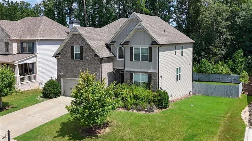 Two-story residence featuring a brick facade with horizontal siding accents, an attached garage, and a concrete driveway