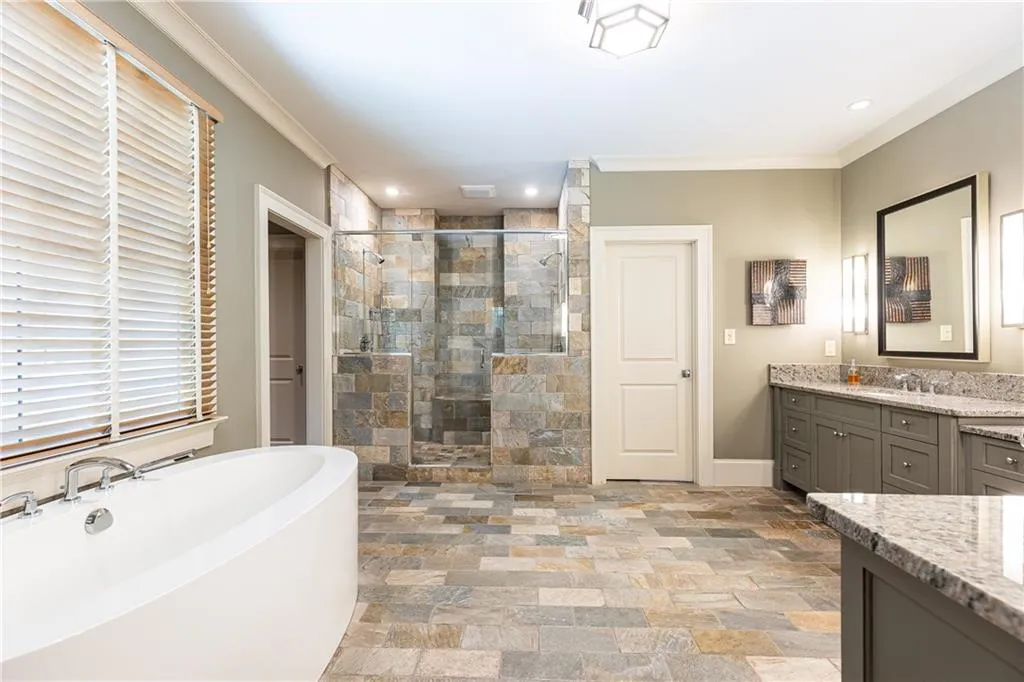 Primary bath features a double shower, double vanities and dressing table as well as two deep walk-in closets.