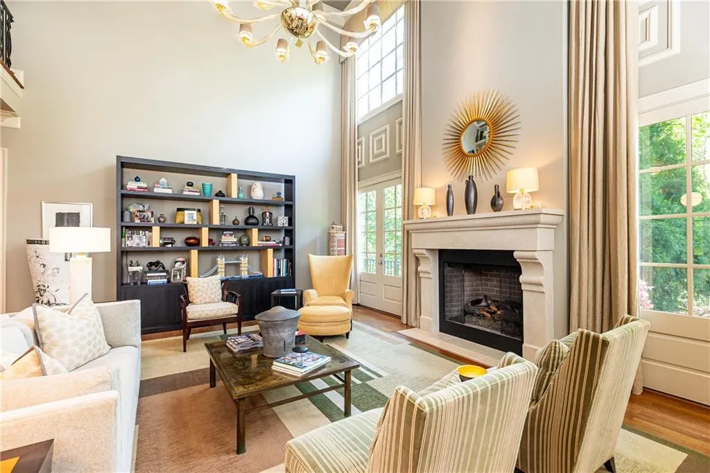 Beautiful two-story living room features dramatic floor-to-ceiling windows and elegant fireplace