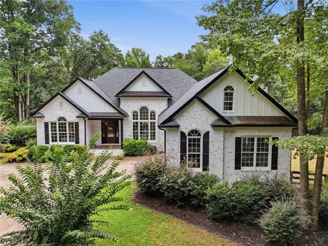 White brick exterior with black shutters, dark shingle roof, and gabled architectural elements