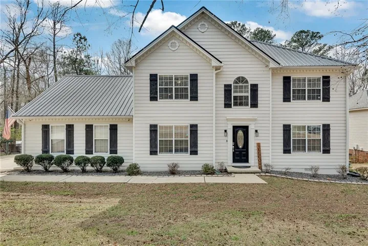 White siding exterior with a metal roof and black shutters