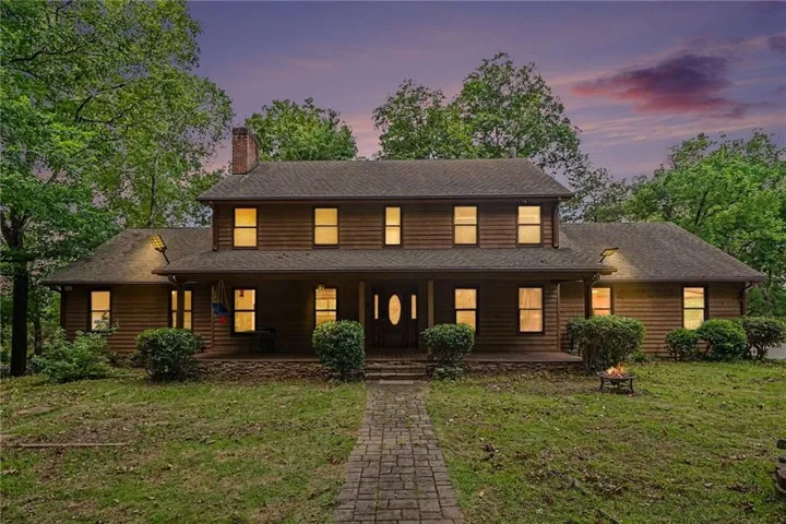 Wood-sided residence featuring a full-width front porch, brick chimney, and a paved walkway