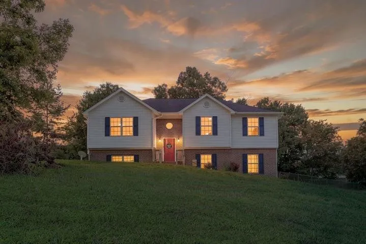 Two-story residence featuring white siding, dark blue shutters, a red entry door, and a brick foundation