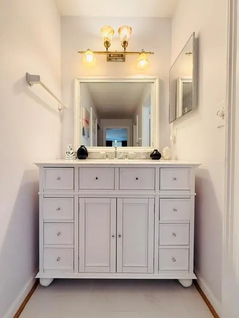 Elegant bathroom vanity featuring a white painted cabinet with multiple drawers and center cabinet doors, polished countertop surface, and dual sink configuration